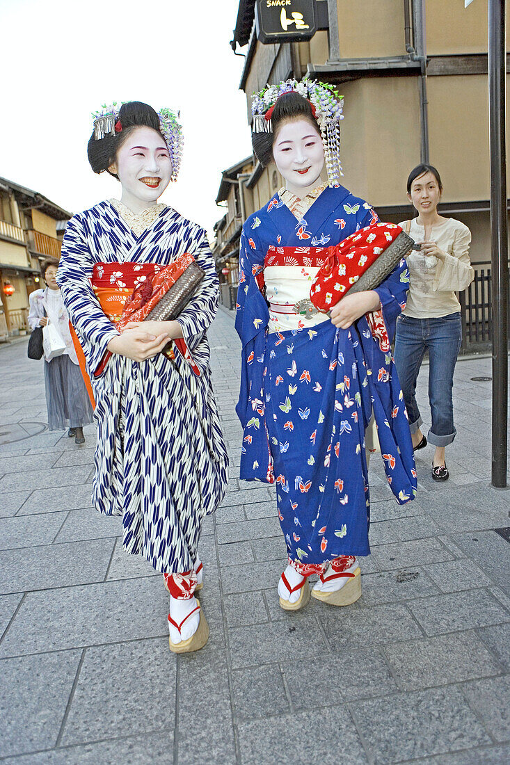 Two Maiko (geisha apprentices) walking to their evening appointment in the traditional quarter of Gion . Kyoto. Kansai, Japan (Model Release)
