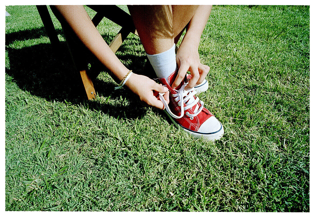 Girl lacing up shoes.