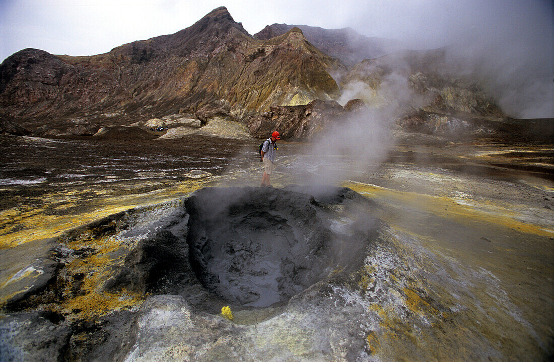 Tourist looking at boiling hot mud on White Island, North Island, New Zealand