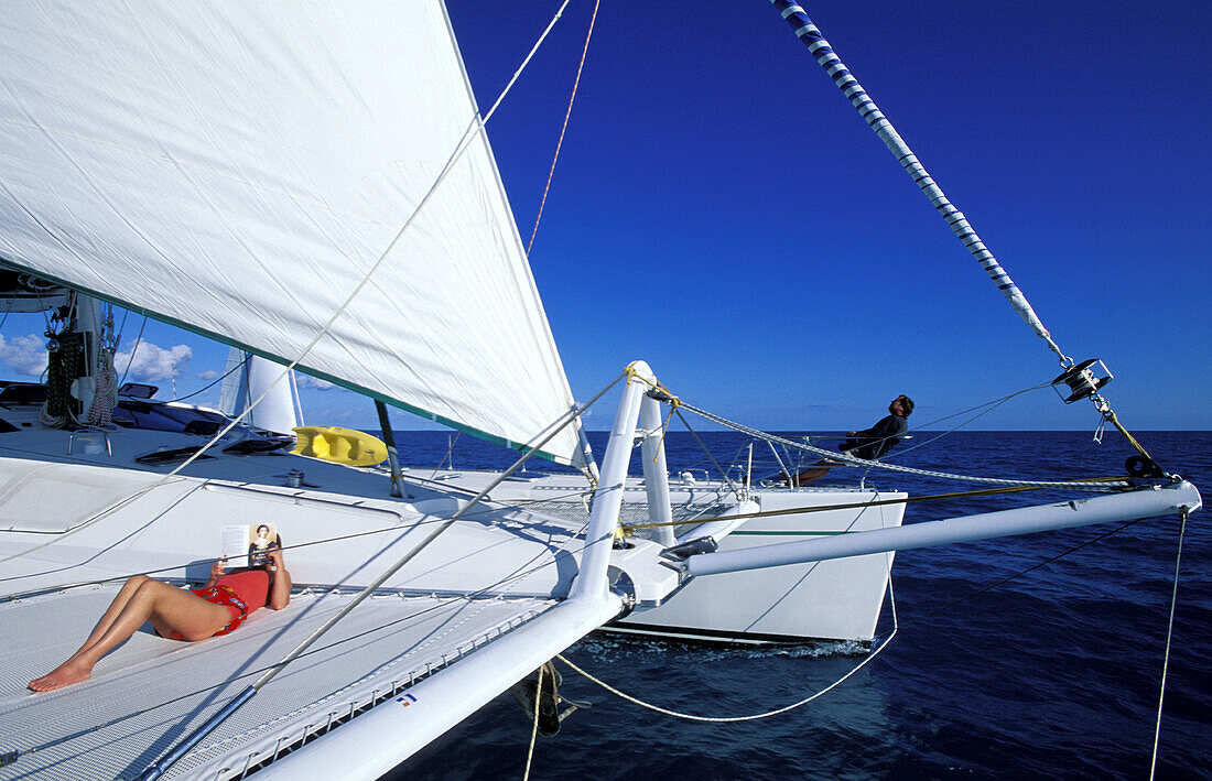 Cruising on a sailboat, woman reading on deck. British Virgin Islands