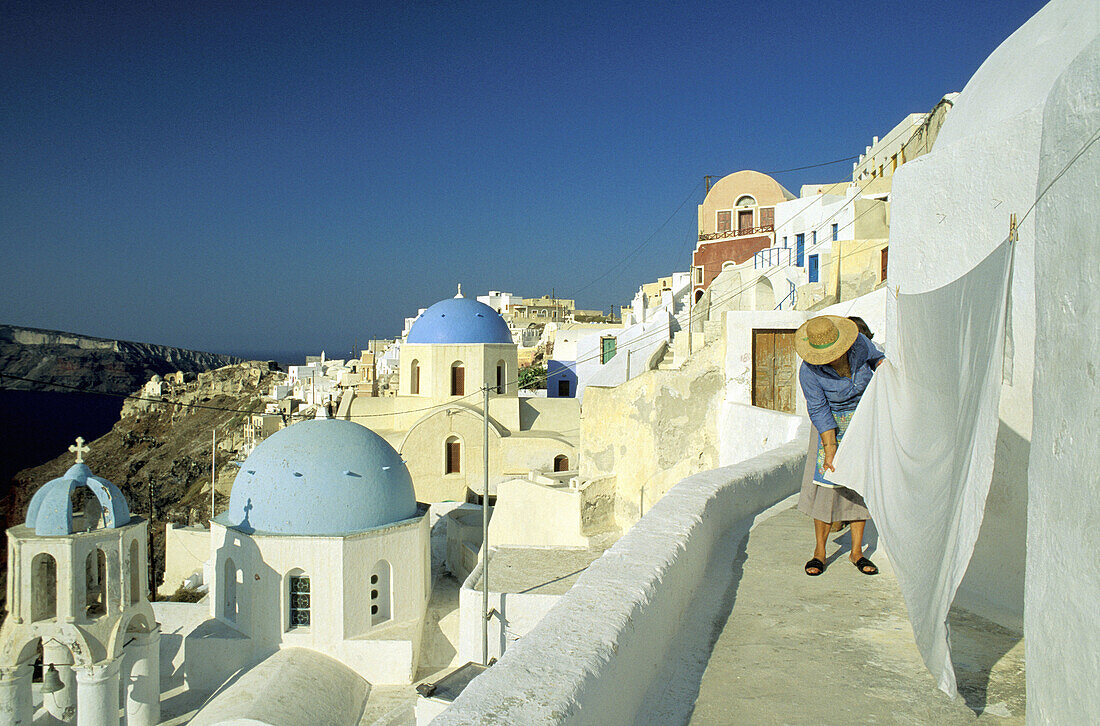 Woman taking care of her drying laundry. Ia village. Santorini (Cyclades). Greece