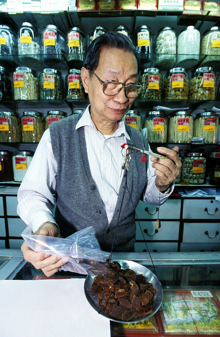 Traditional Herbalist at work in his shop. Wanchai. Hong Kong. China
