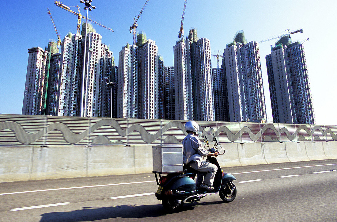 Motor scooter on the airport highway, apartments building site at back. Hong Kong. China