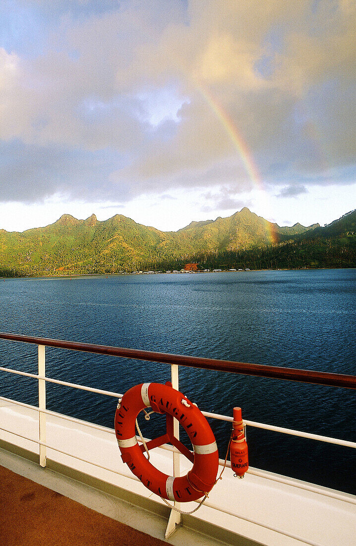 Rainbow over Huahine Island and deck of MS Paul Gauguin cruise ship. French Polynesia