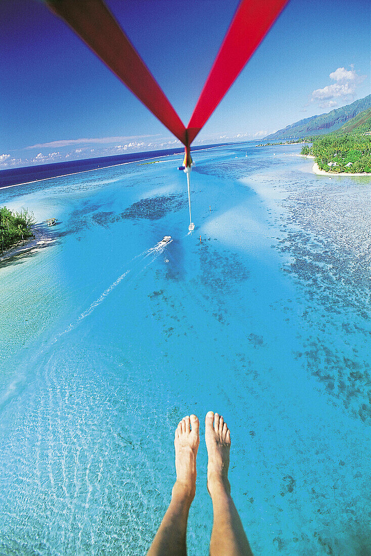Parasailing over the Moorea lagoon, photographers feet at fore. French Polynesia