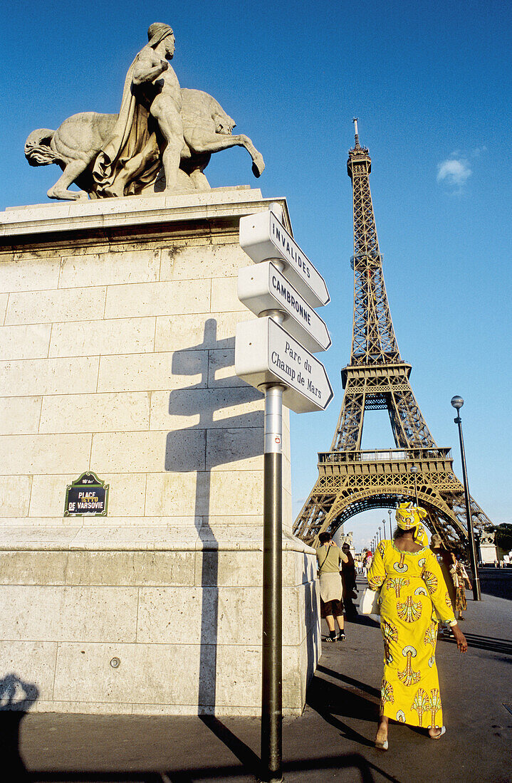 African woman in yellow typical dress at Pont d Iena in front of Eiffel tower. Paris. France