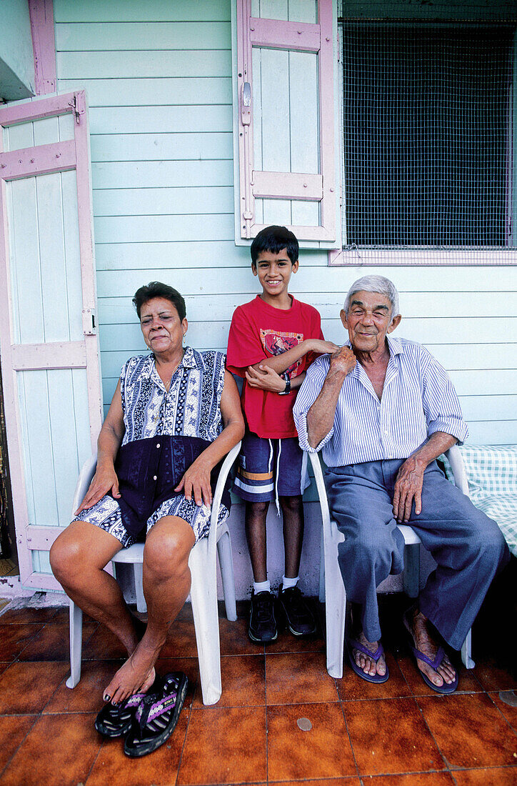 Boy and grandparents at their Creole hut built in colonial style. Réunion Island (France)