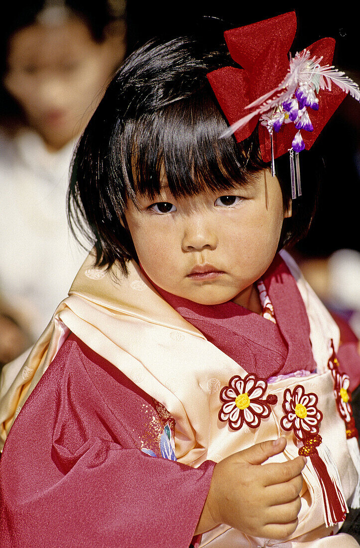 Young girl in traditional dress for the children festival. The Miyajima island, 20 Km south of Hiroshima, shelters the important shrine of Itsukushima, founded in the 9th century and famous for its wood portico (Torii), set up in the sea. Japan.