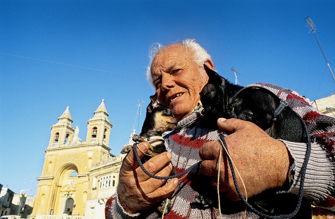 Mr. John Xirri, retired, selling new born puppies at Sunday market. Marsaxlokk. Malta.