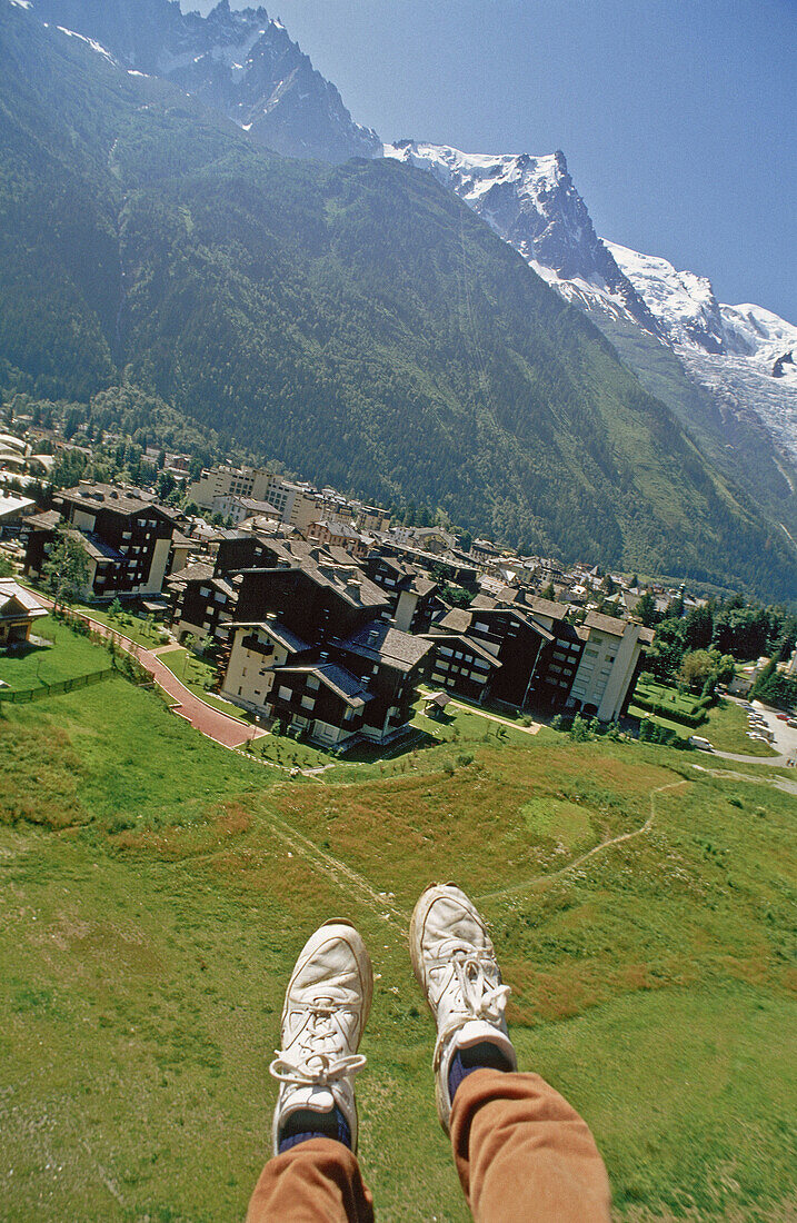 Aerial of the Mont-Blanc massif and city from a paraglider. Photographer s bad shoes at fore. Chamonix and its valley. Haute-Savoie. France.