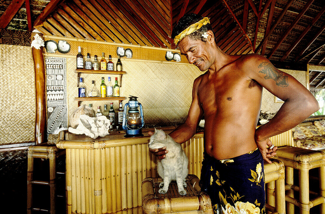 Mr Chevalier, manager, and his grey cat. Cabins hotel for wealthy visitors playing Robinson Crusoe on a remote islet. Kia Ora luxury hotel. Rangiroa atoll. Tuamotus archipelago. French Polynesia (Model released)