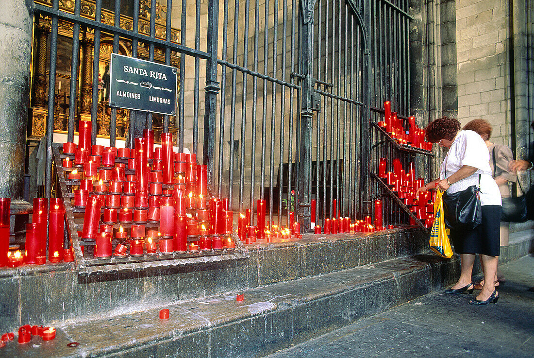 Women lighting candles at Saint Rita chapel in the cathedral. Barcelona. Spain