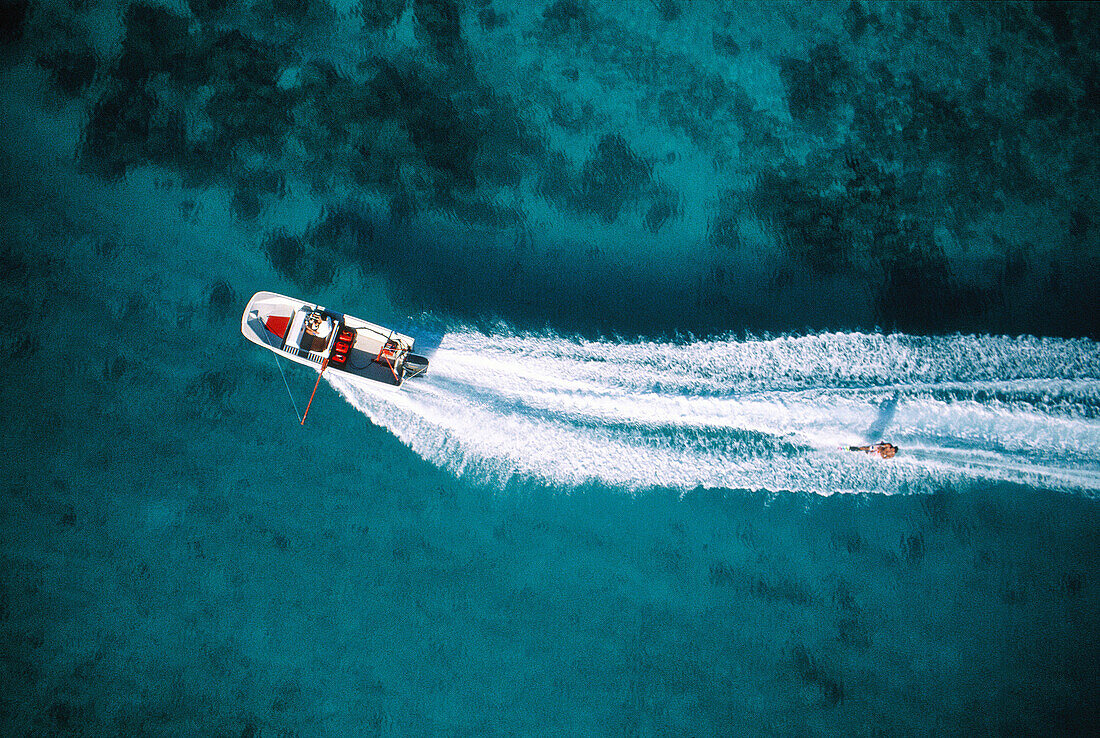 Aerial of a boat pulling a waterskier on the lagoon. Moorea island. Windward Islands. French Polynesia