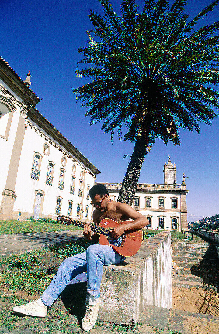 Man playing guitar in front of Mineralogy Museum. Historic city of Ouro Preto. Minas Gerais. Brazil