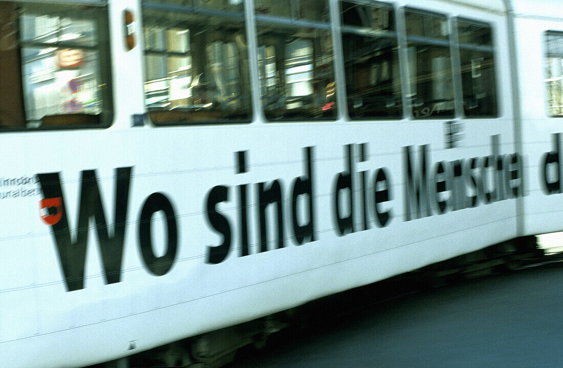Blurred tram passin by with advertisiment Where are the men... . Innsbruck. Tyrol. Austria