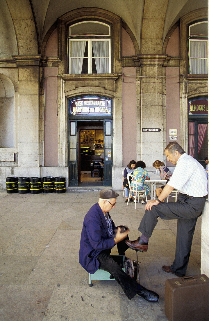 Shoeshiner and Cafe Martinho da Arcada in background. Praça do Comércio. Lisbon. Portugal