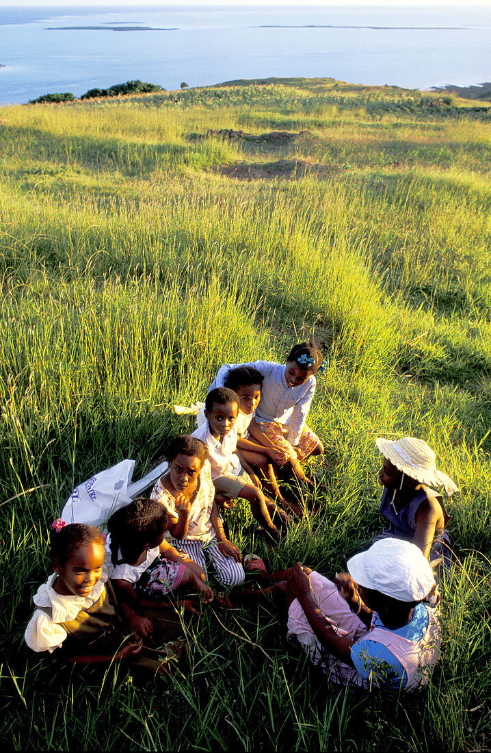 Group of children gathered in a field at sunset. Rodrigues Island. Mauritius