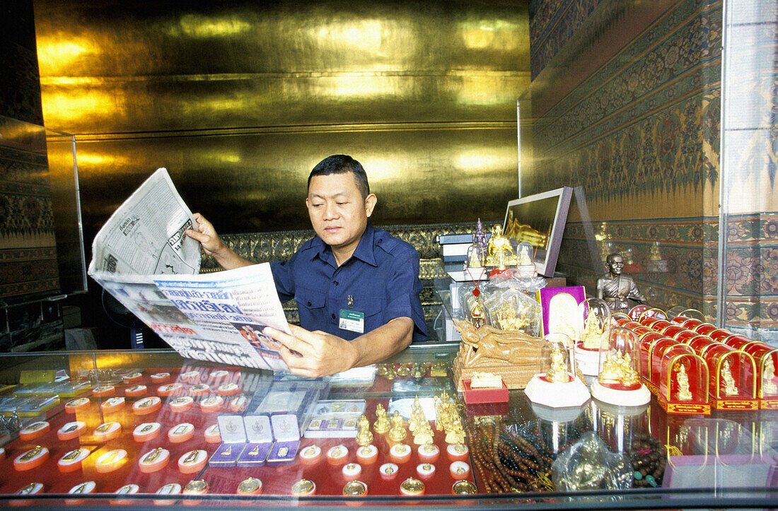 Souvenirs seller reading the newspaper. Wat Pho Temple. The Reclining Buddha. Bangkok. Thailand