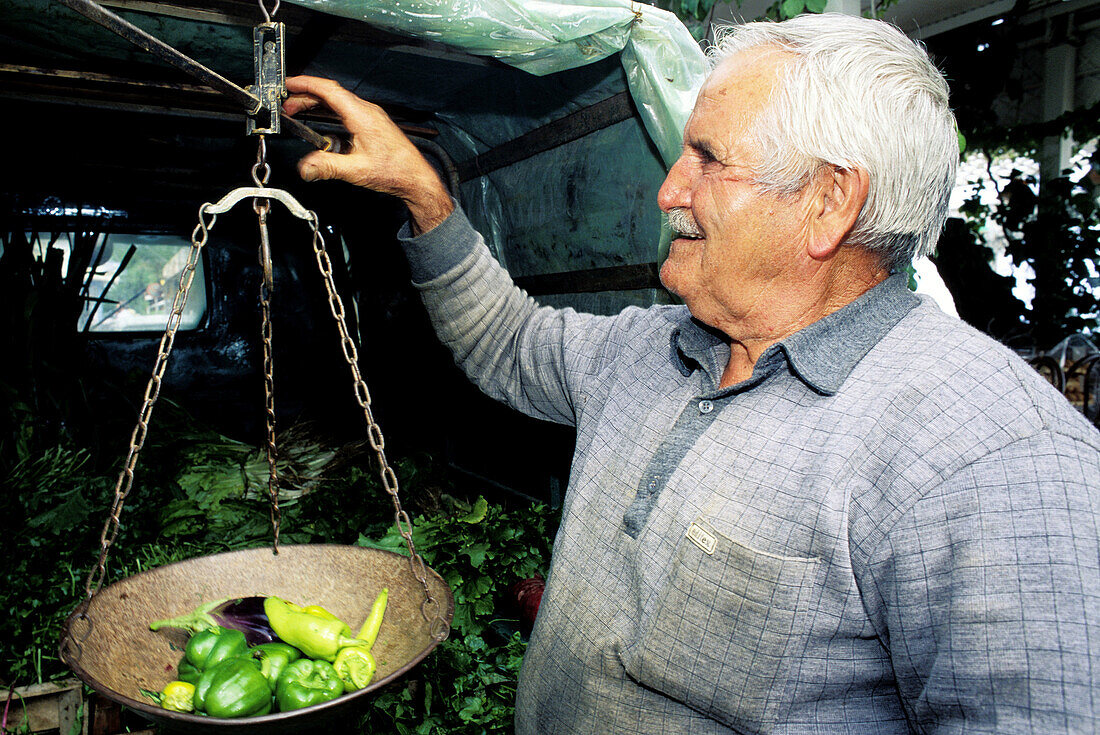 Man weighting vegetables for sale in his van. Hersonissou, Crete. Greece