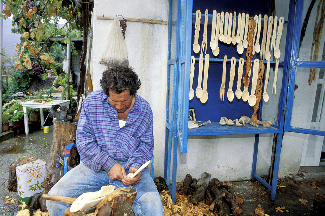 Craftsman carving wooden spoons. Lassithi plateau, Crete. Greece