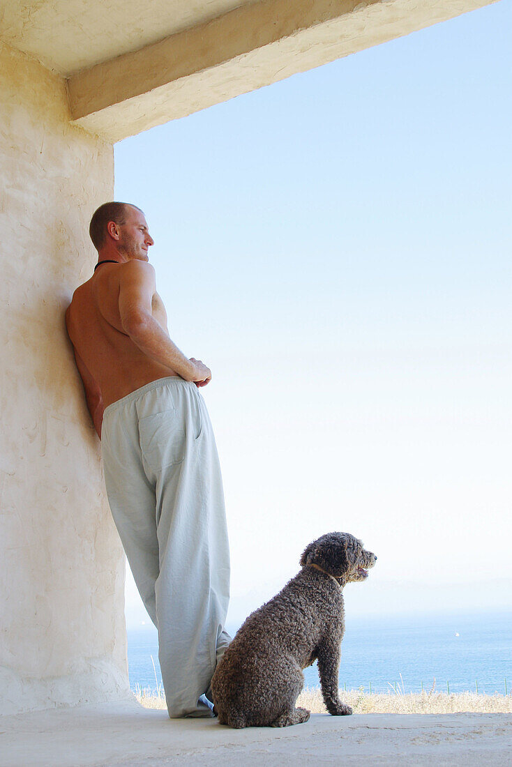 man and dog admiring view from seaside house
