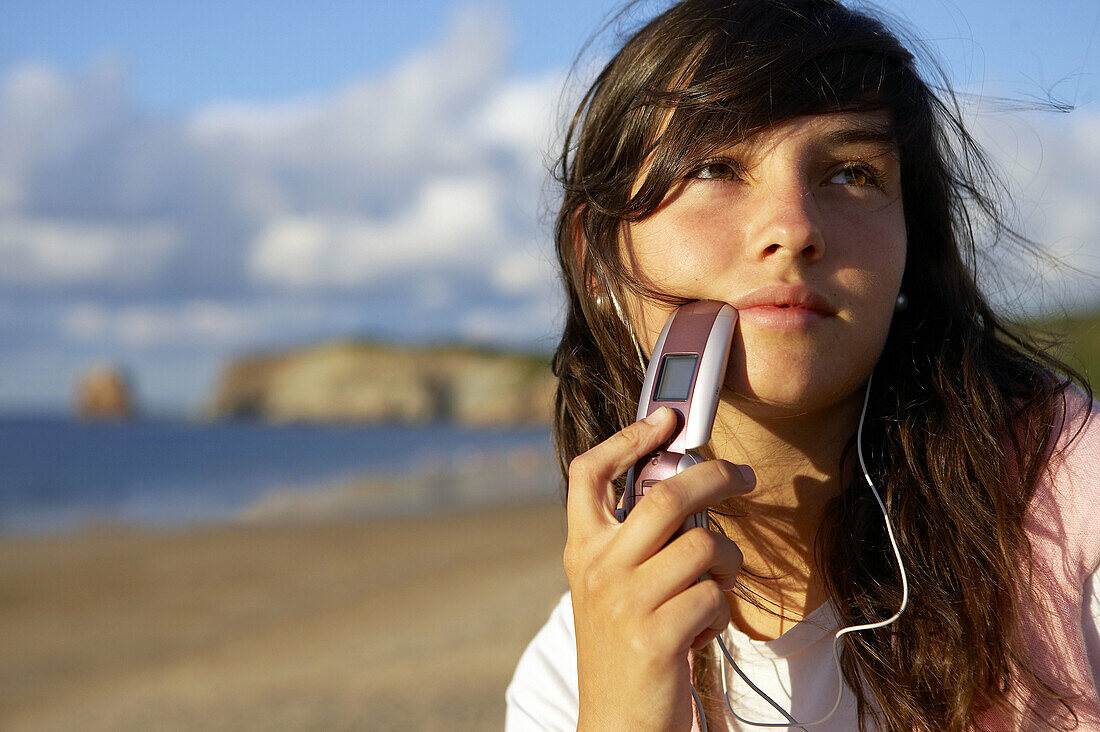 16-jähriger Jugendlicher hört Musik mit einem MP3-Handy. Strand von Hendaye. Aquitanien. Frankreich.