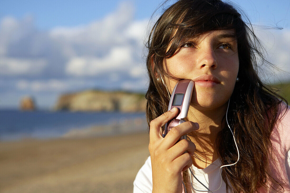 16 years old teenager listening to music in a MP3 mobile phone. Hendaye beach. Aquitaine. France.