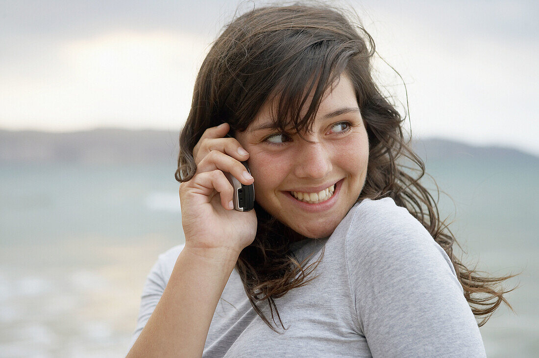 16 Jahre altes Teenie-Mädchen benutzt Handy am Strand