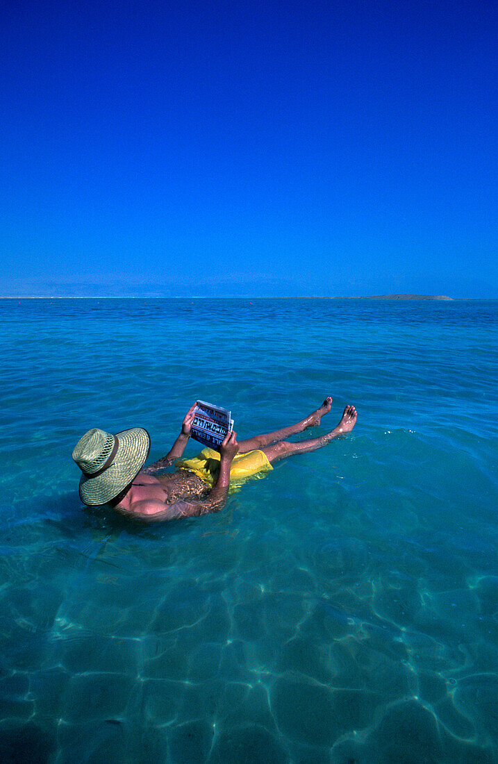Floating man reading hebrew newspaper, Ein bokek, Dead sea, Israel.