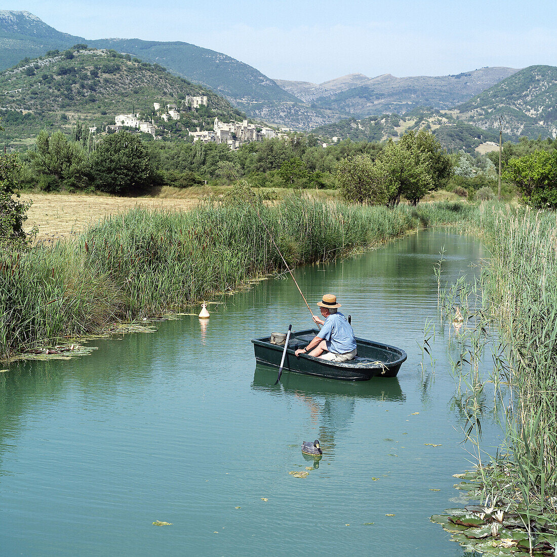 Elderly man fishing from row boat in a river. Drôme, Provence. France.