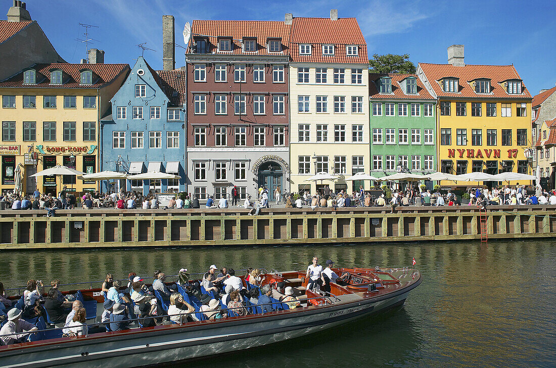 Tour boats, ancient houses and waterfront cafe terraces at Nyhavn ( New Harbor ), Copenhagen. Denmark