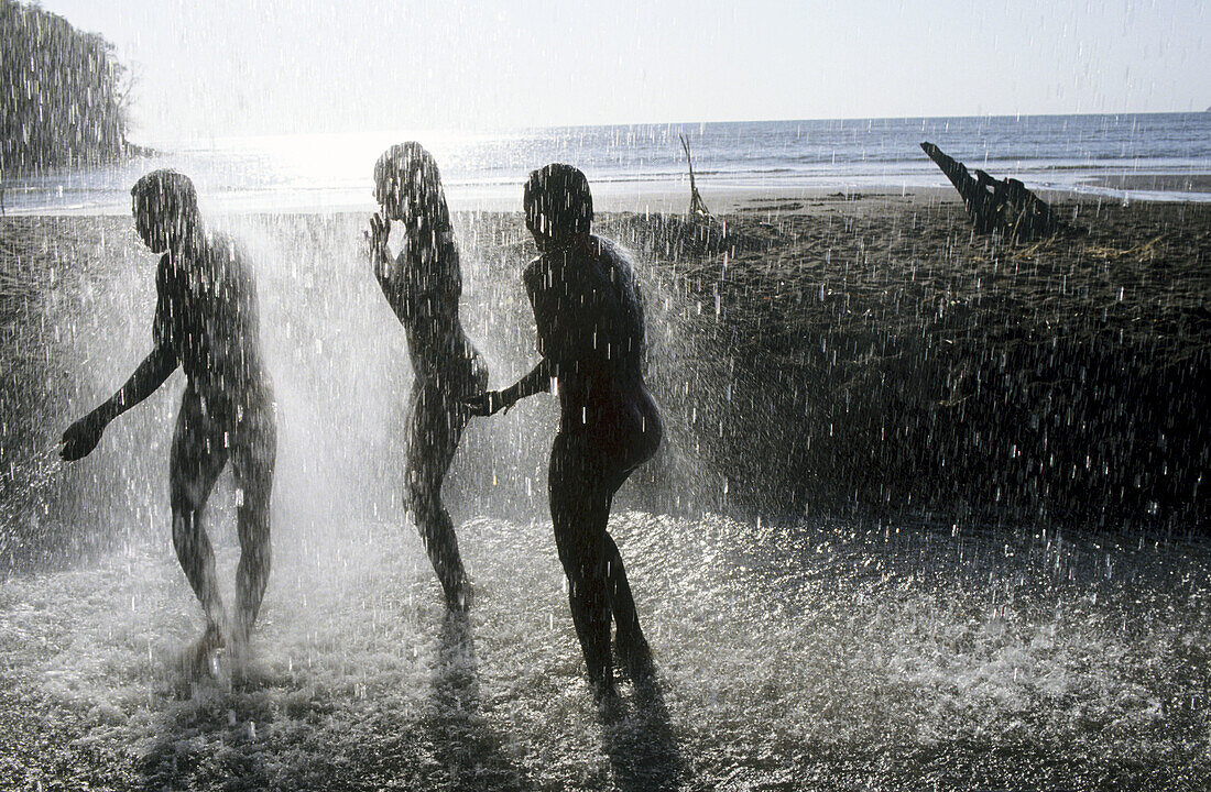Teenagers under a waterfall. Mayotte, island of the Comoros archipelago in the Indian Ocean, French territory.