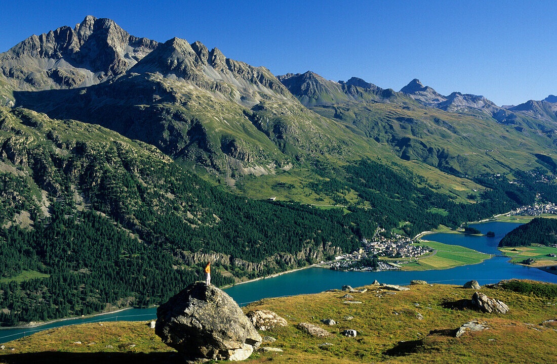 young woman on rock in alpine pasture high above lake Silvaplaner See and Champfer (Champfér) See, Engadin, Grisons, Switzerland