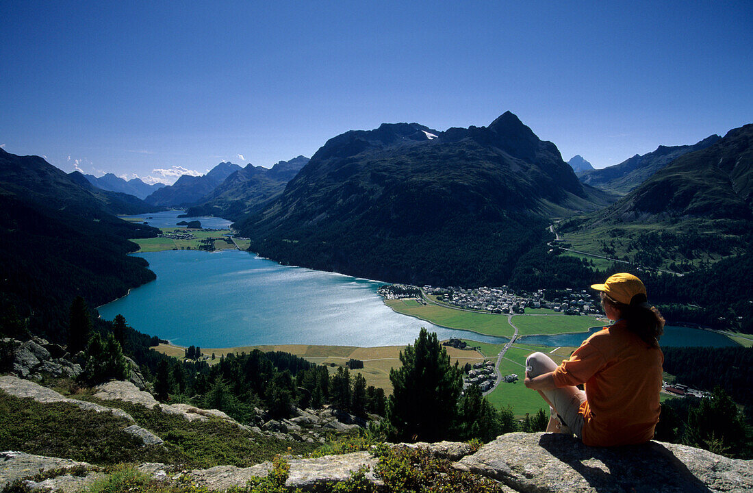 junge Frau auf Felsabsatz hoch über dem Silser, Silvaplaner und Champfer (Champfér) See , Engadin, Graubünden, Schweiz