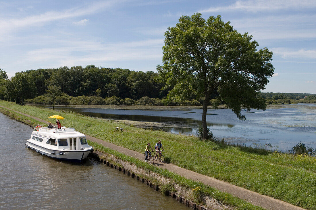 Radfahrer und Crown Blue Line Calypso Hausboot am Canal de la Marne au Rhin, nahe Etang de Gondrexange See, Elsass, Frankreich, Europa