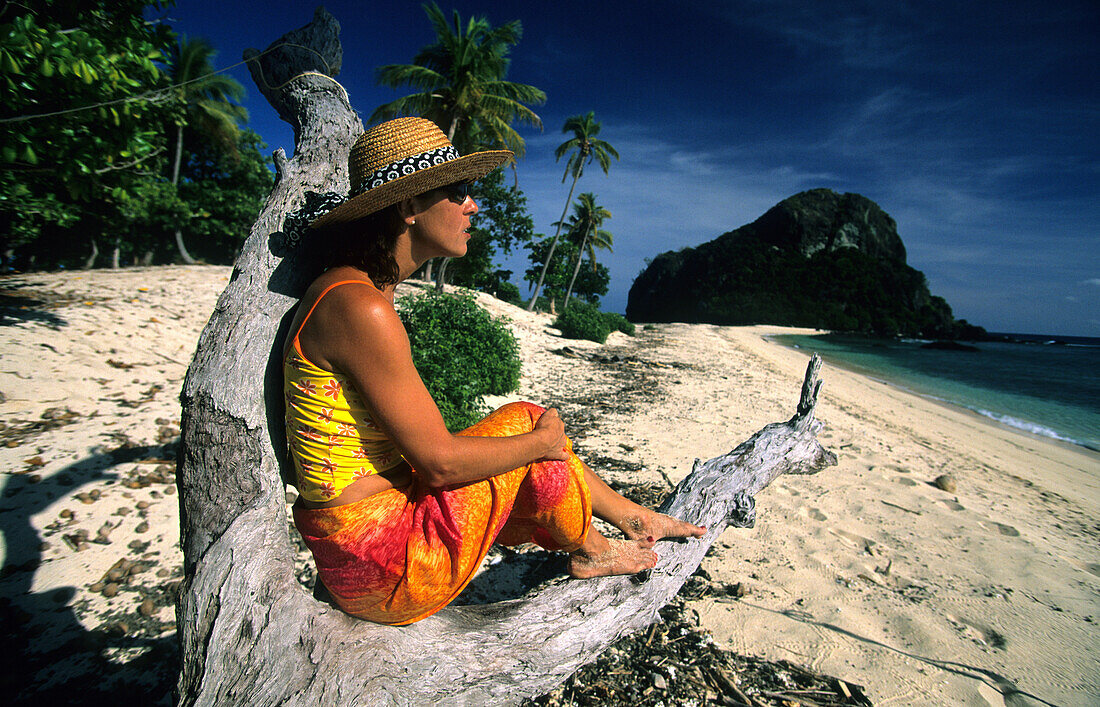 Eine Frau sitzt am Strand, Navadra Island, Mamanuca Gruppe, Fidschi, Südsee