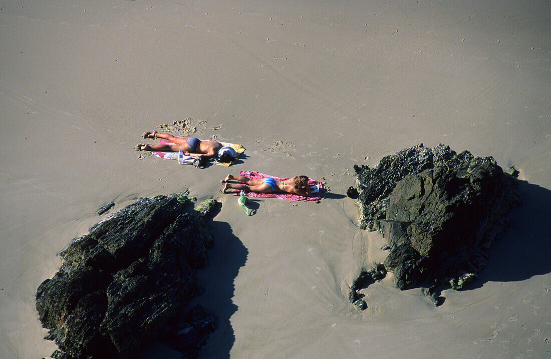 Zwei Leute beim Sonnenbaden am Clarkes Beach, Byron Bay, New South Wales, Australien