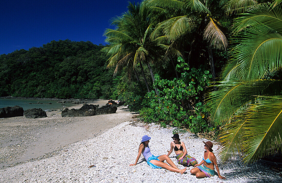 Drei junge Frauen sitzen am Strand, Muggy Beach, Dunk Island, Great Barrier Reef, Australien