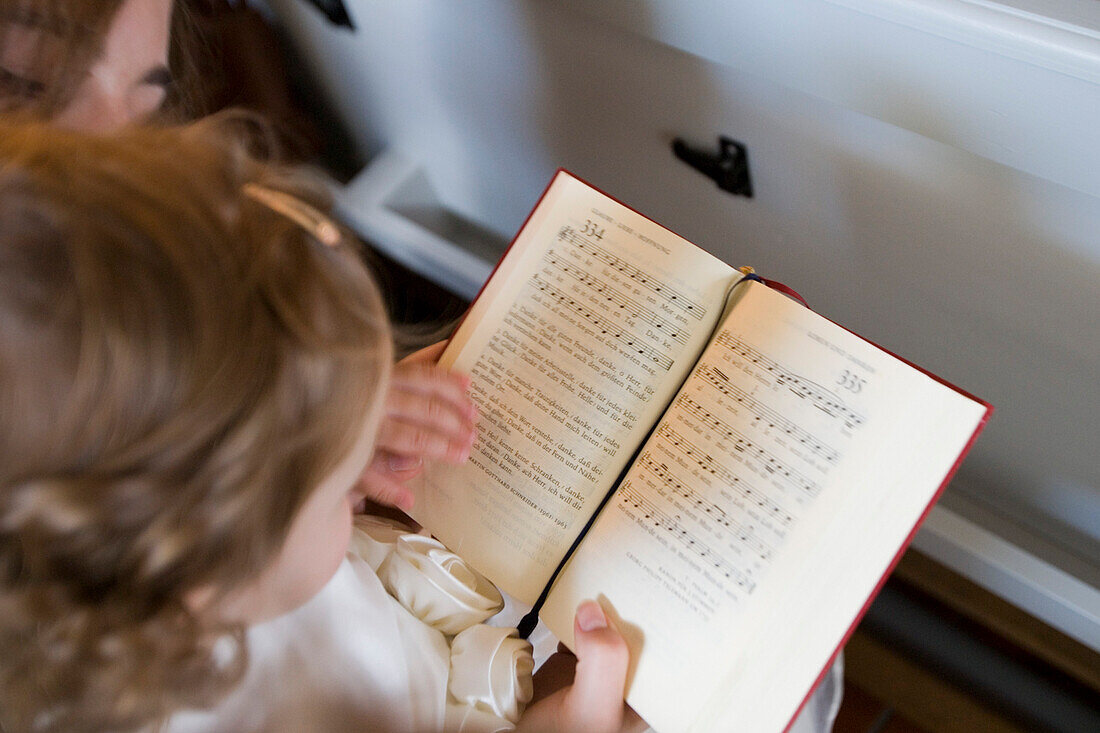 Girl with hymnbook attending divine service during a wedding, Hauneck Oberhaun, Hesse, Germany