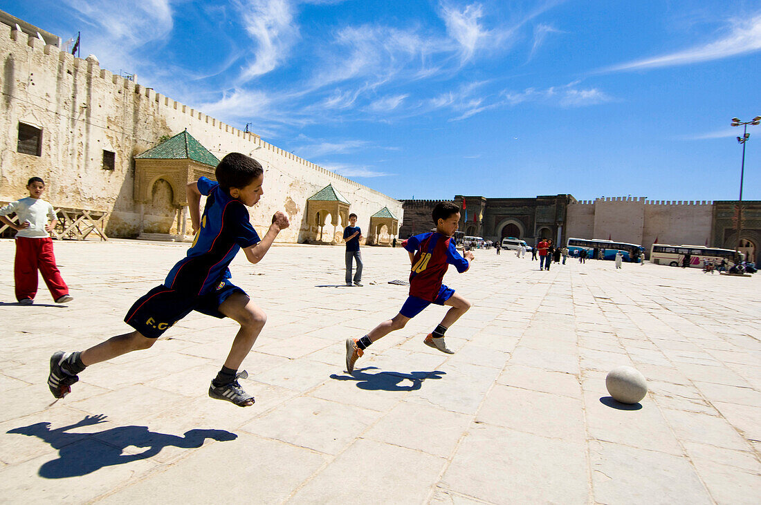 Fußball spielende Jungen, Eine Gruppe von Jungen spielen Fußball am Platz von Meknes, Marokko, Afrika