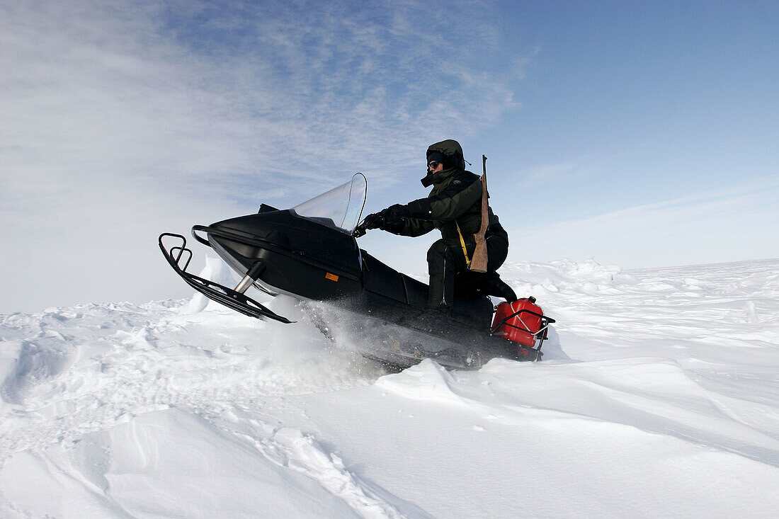 Snow machine on frozen sea ice of Hudson Bay in late winter. Churchill, Manitoba, Canada. Model and property released.
