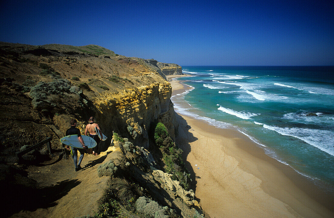 Two men carrying surfboards, surfer on the way to the surf, Port Campbell National Park, Victoria, Australia