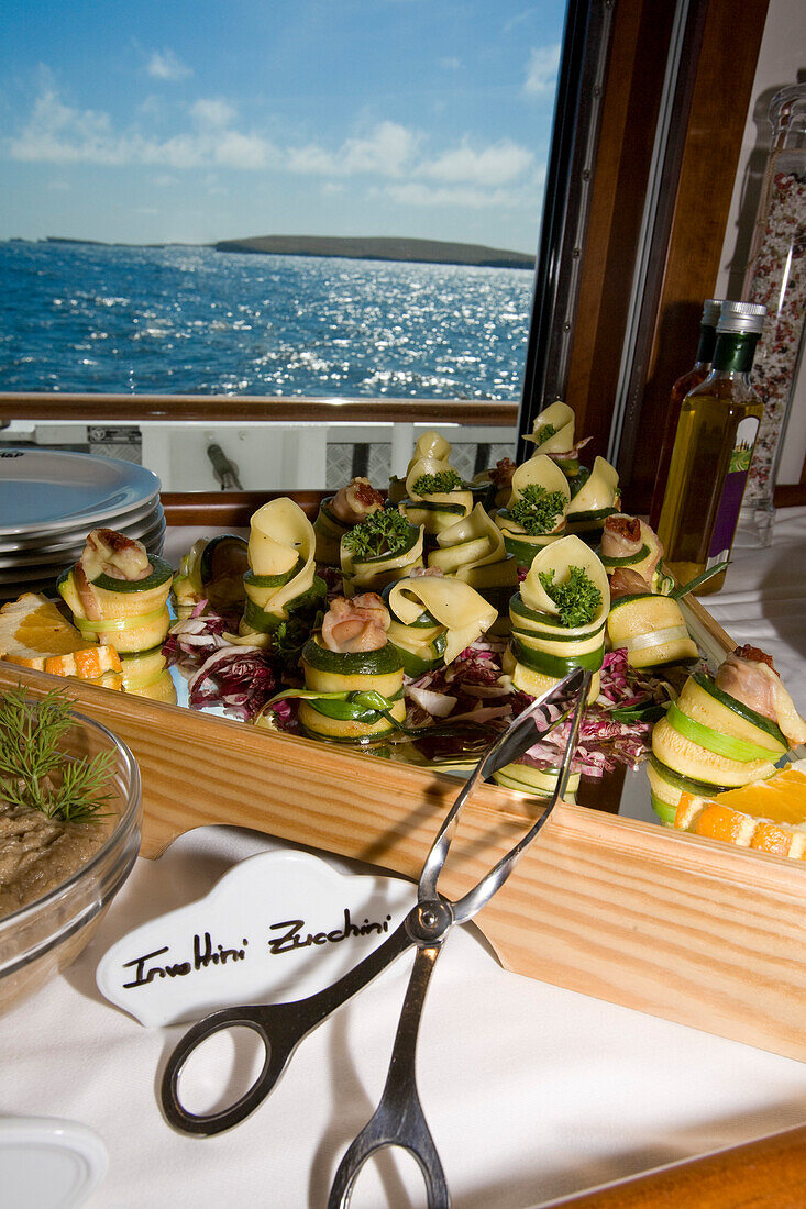 Delicious food on board the yacht Hanse Explorer, cold buffet with zucchini, courgette, and vegetables, sea and Scottish coast in the background, Shetland Islands, Scotland, Great Britain