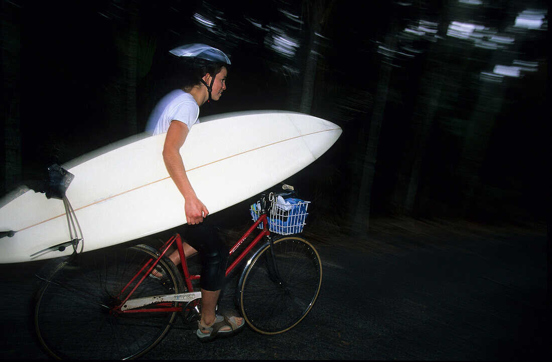 Ein Surfer transportiert sein Surfbrett mit dem Fahrrad, Lord Howe Island, Australien