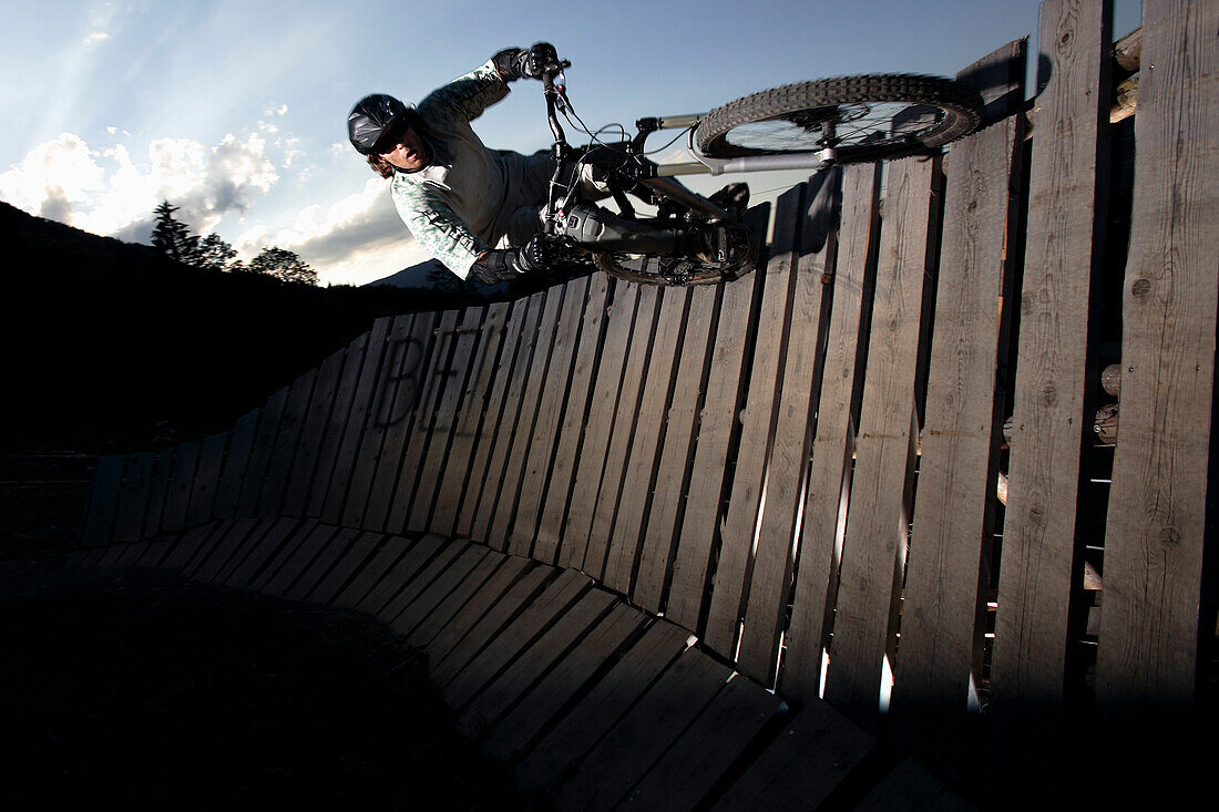 Mountain biker passing wallride, Oberammergau, Bavaria, Germany