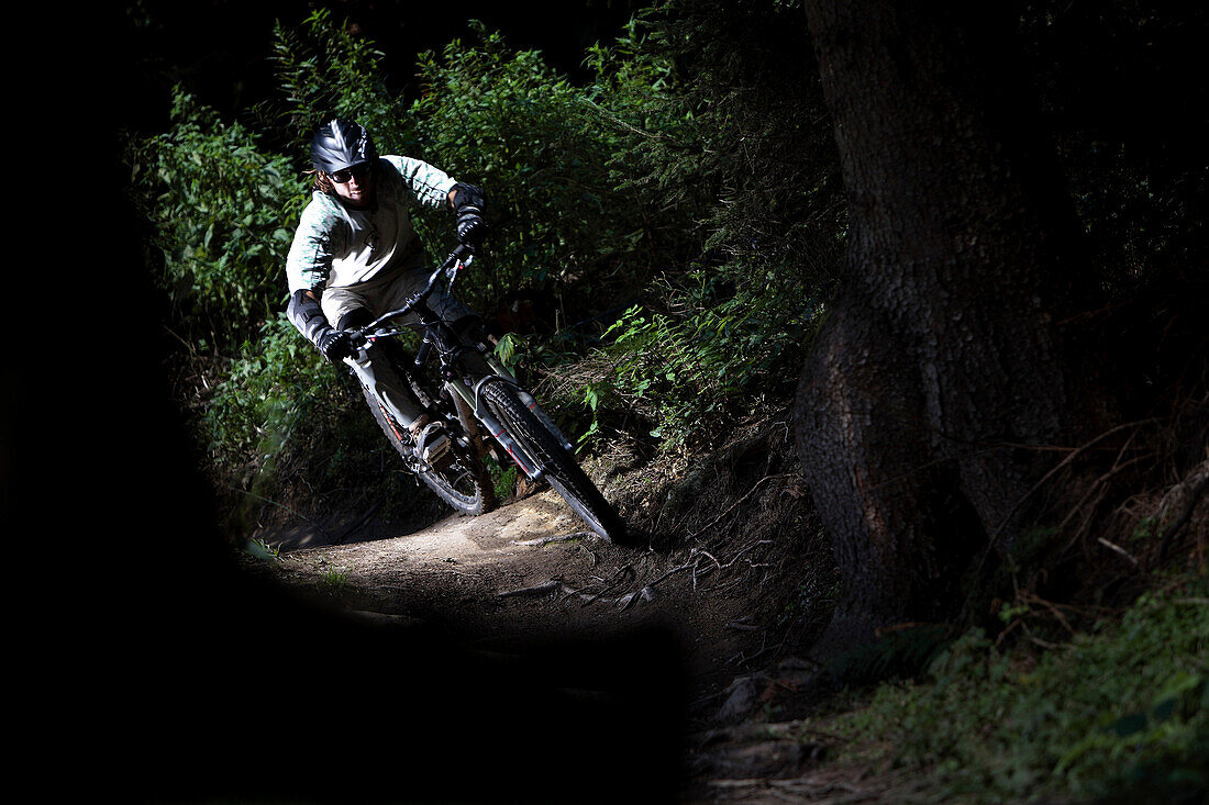 Young man riding a mountainbike in the forest, Oberammergau, Bavaria, Germany