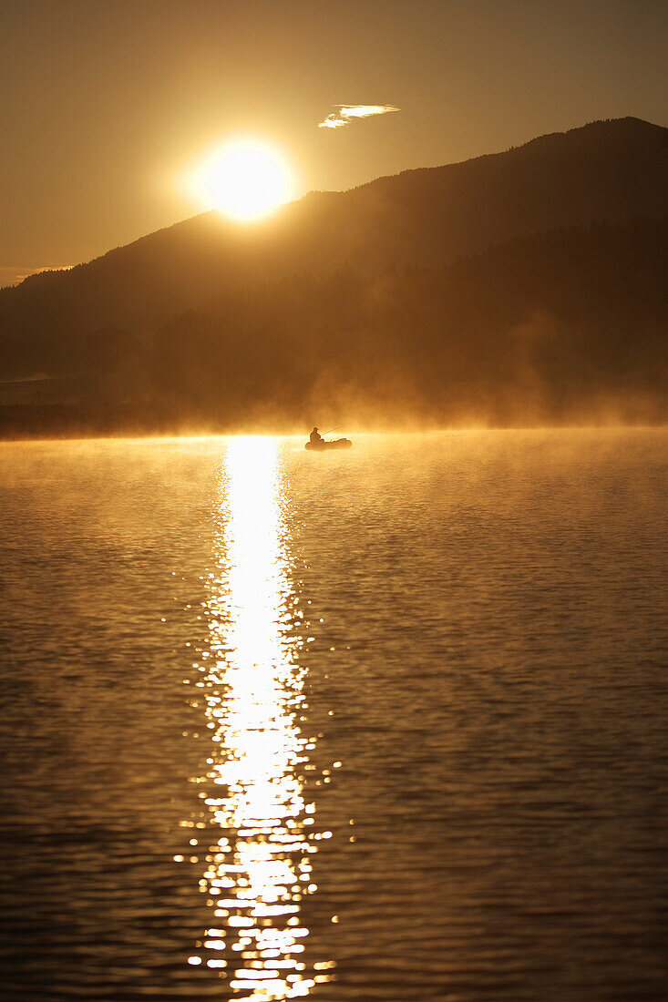 Man fishing on Lake Alpsee in the morning, Schwangau, Bavaria, Germany