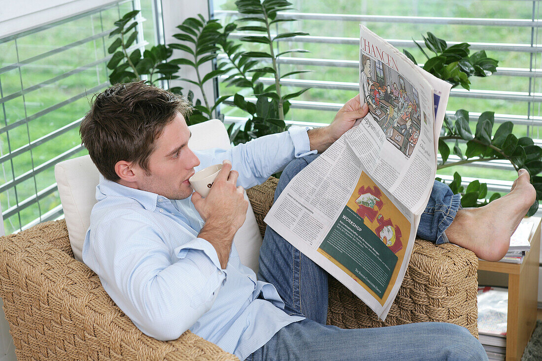 Young man reading a newspaper, Munich, Germany