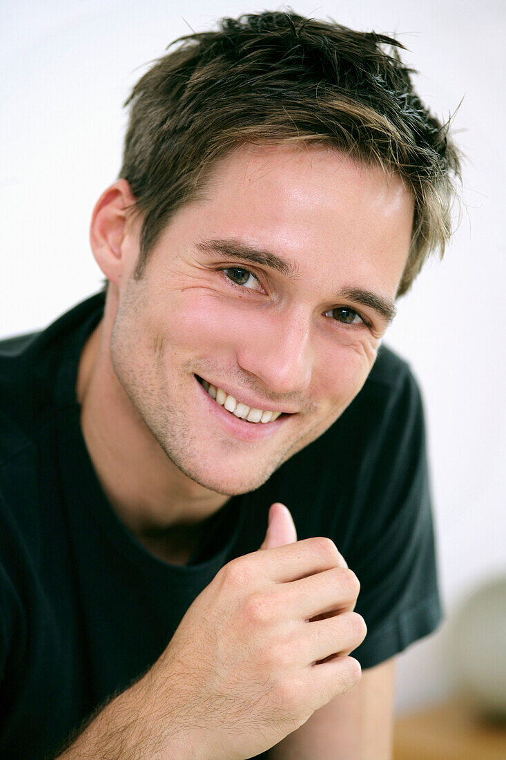 Junger Mann lächelt in die Kamera, München, Deutschland