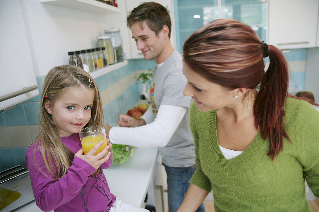 Familie in der Küche, Tochter trinkt ein Glas Saft, München, Deutschland